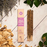 Palo Santo sticks with packaging on a wooden surface with herbs and leaves.