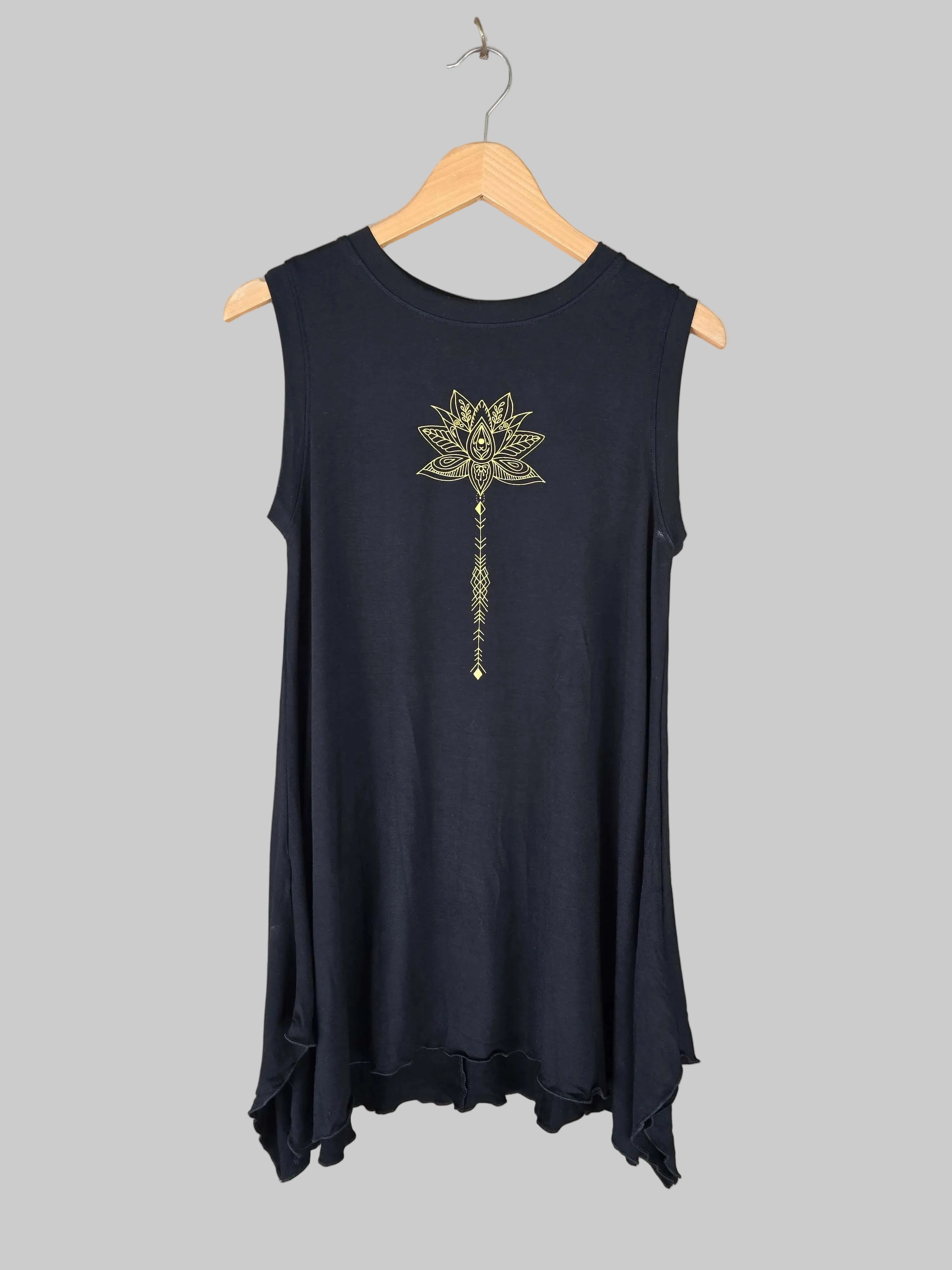 Black sleeveless top with a decorative design on a hanger against a neutral wall.