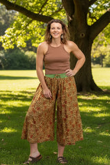Woman wearing a brown tank top and patterned wide-leg pants in a park 