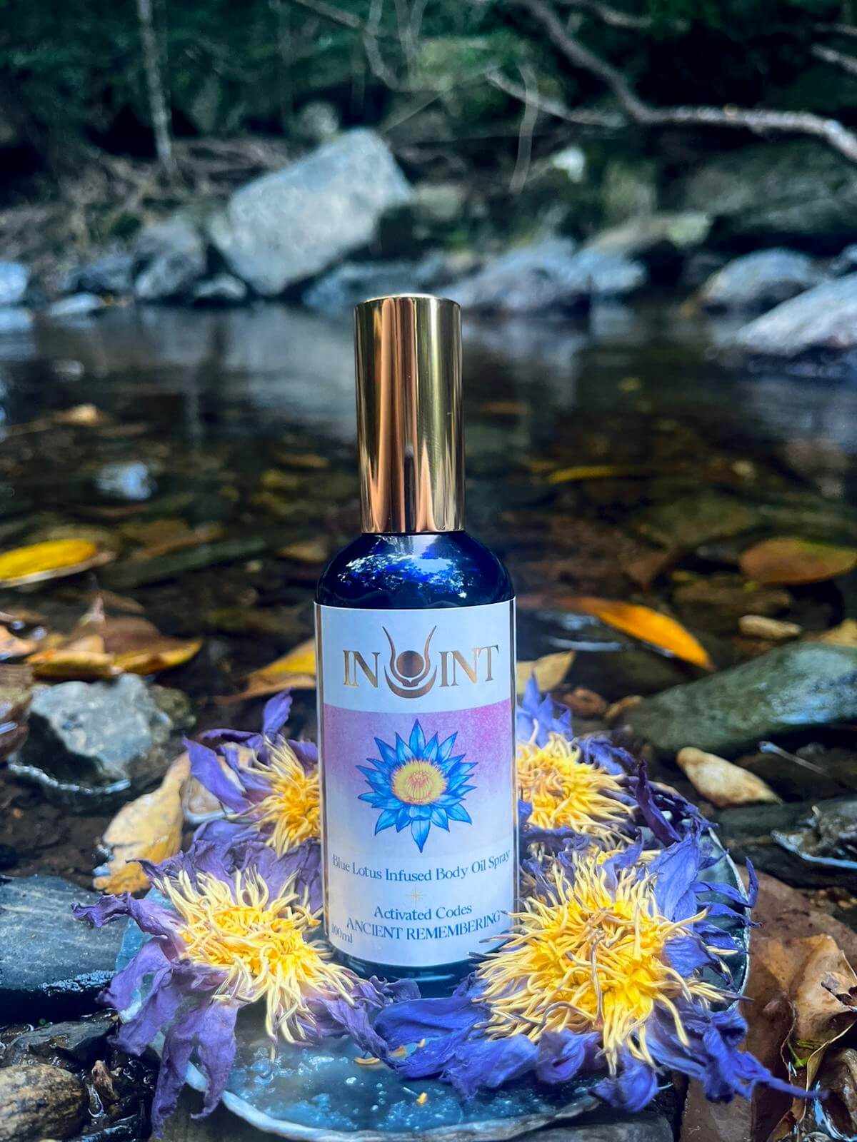 Bottle of Inoint elixir with flowers and water in the background