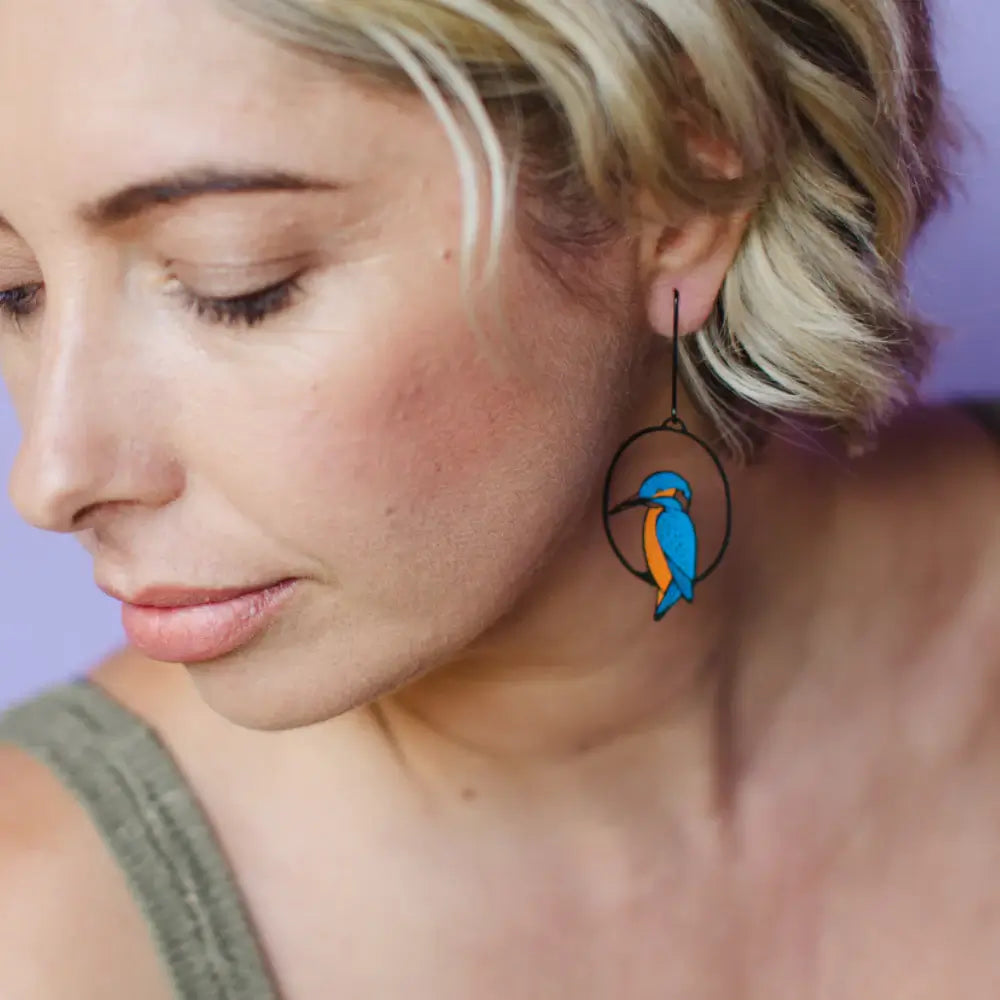 Close-up of a woman wearing a unique earring with a blue bird design.