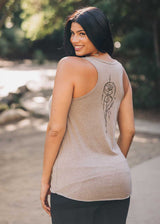 Woman wearing a beige tank top with a dreamcatcher design outdoors