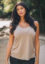 Woman wearing a beige tank top outdoors with blurred background