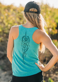 Person wearing a teal tank top with a black design outdoors