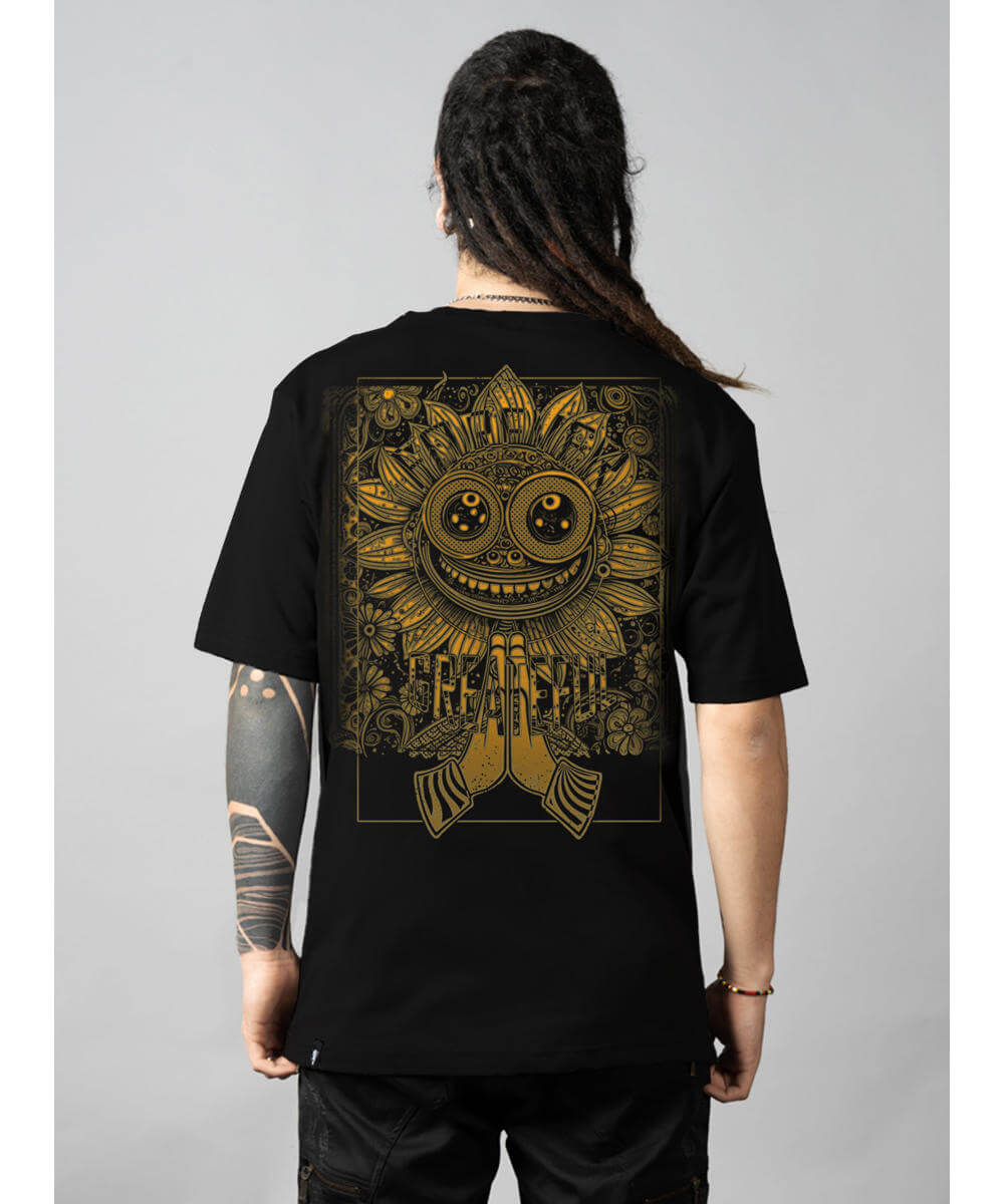 Person wearing a black t-shirt with gold intricate design on the back against a gray background