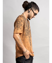 Man wearing a brown t-shirt with intricate designs on a plain background