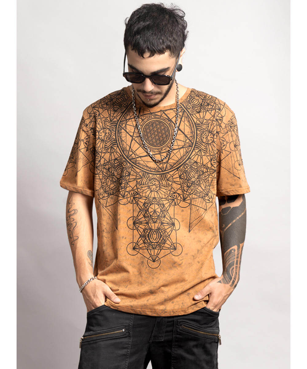 Man wearing a brown t-shirt with geometric designs on a plain background