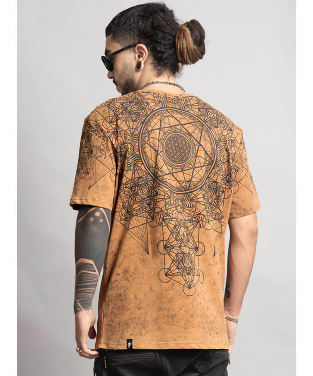 Man wearing a brown t-shirt with intricate designs on the back, standing against a plain background.