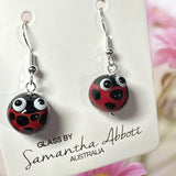 Pair of ladybug-themed earrings on a branded card with 'Glass by Samantha Abbott Australia' text.