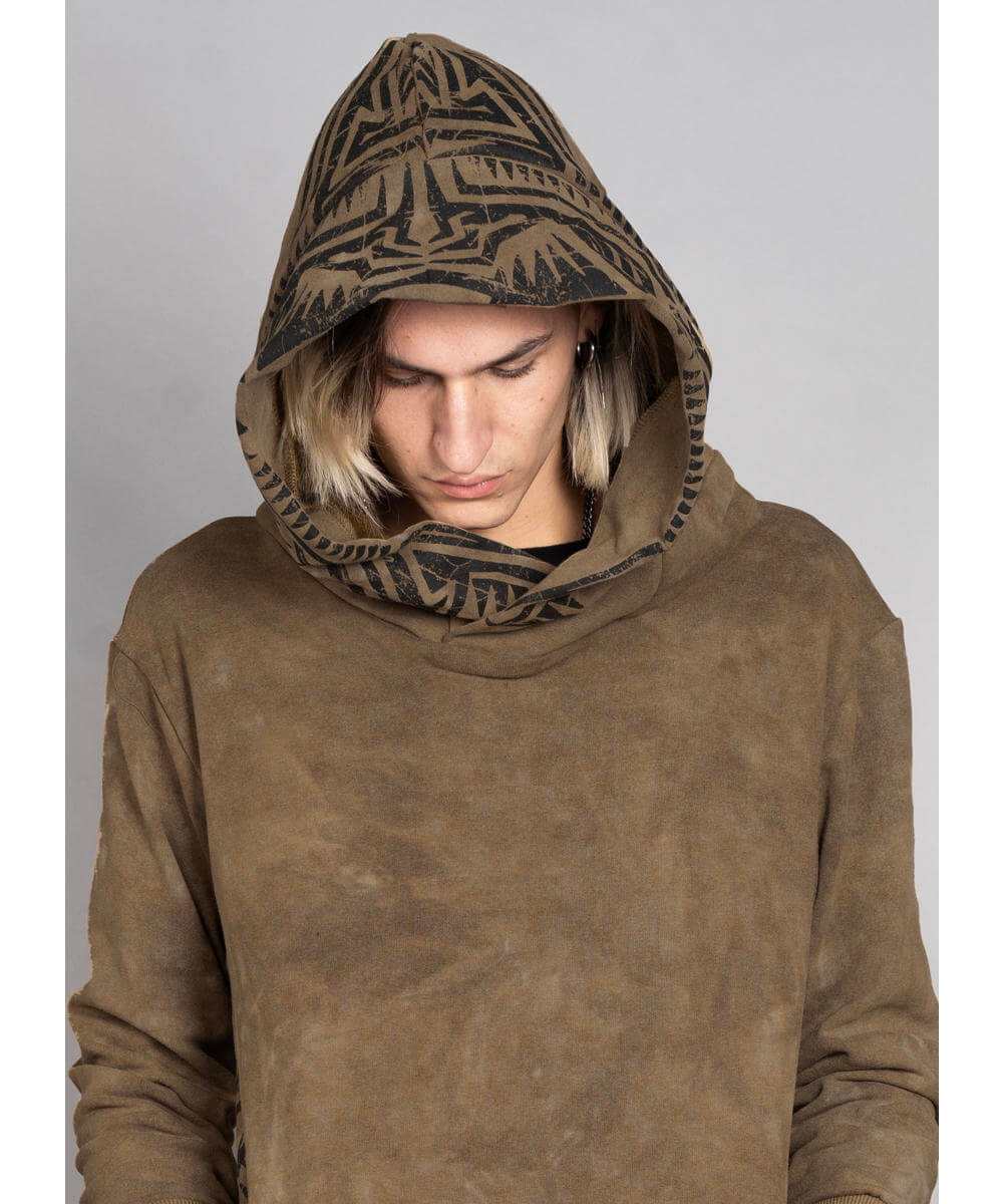 Person wearing a brown hooded sweatshirt with a patterned hood against a gray background