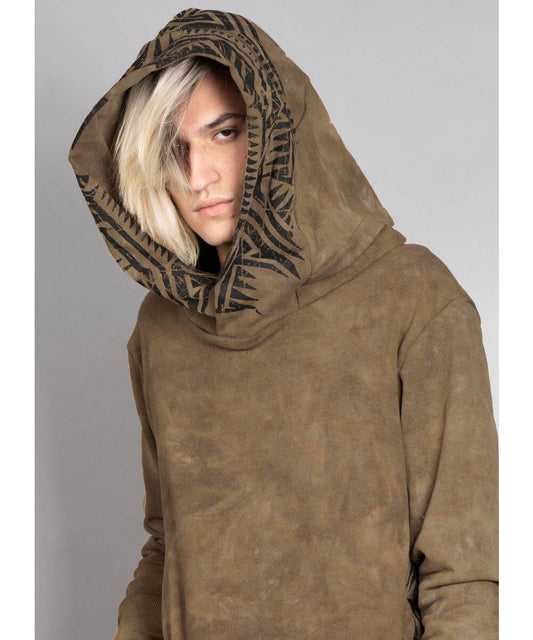 Person wearing a brown hoodie with a patterned hood against a gray background