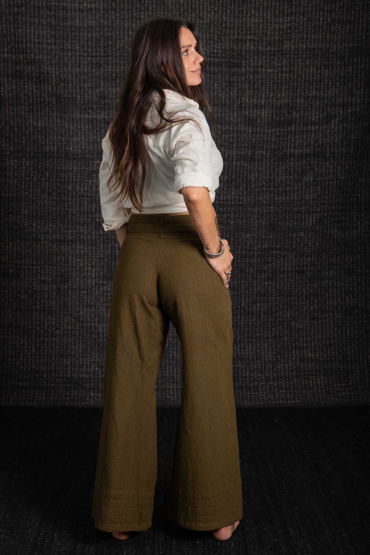 lady in green pants white top with dark bacground