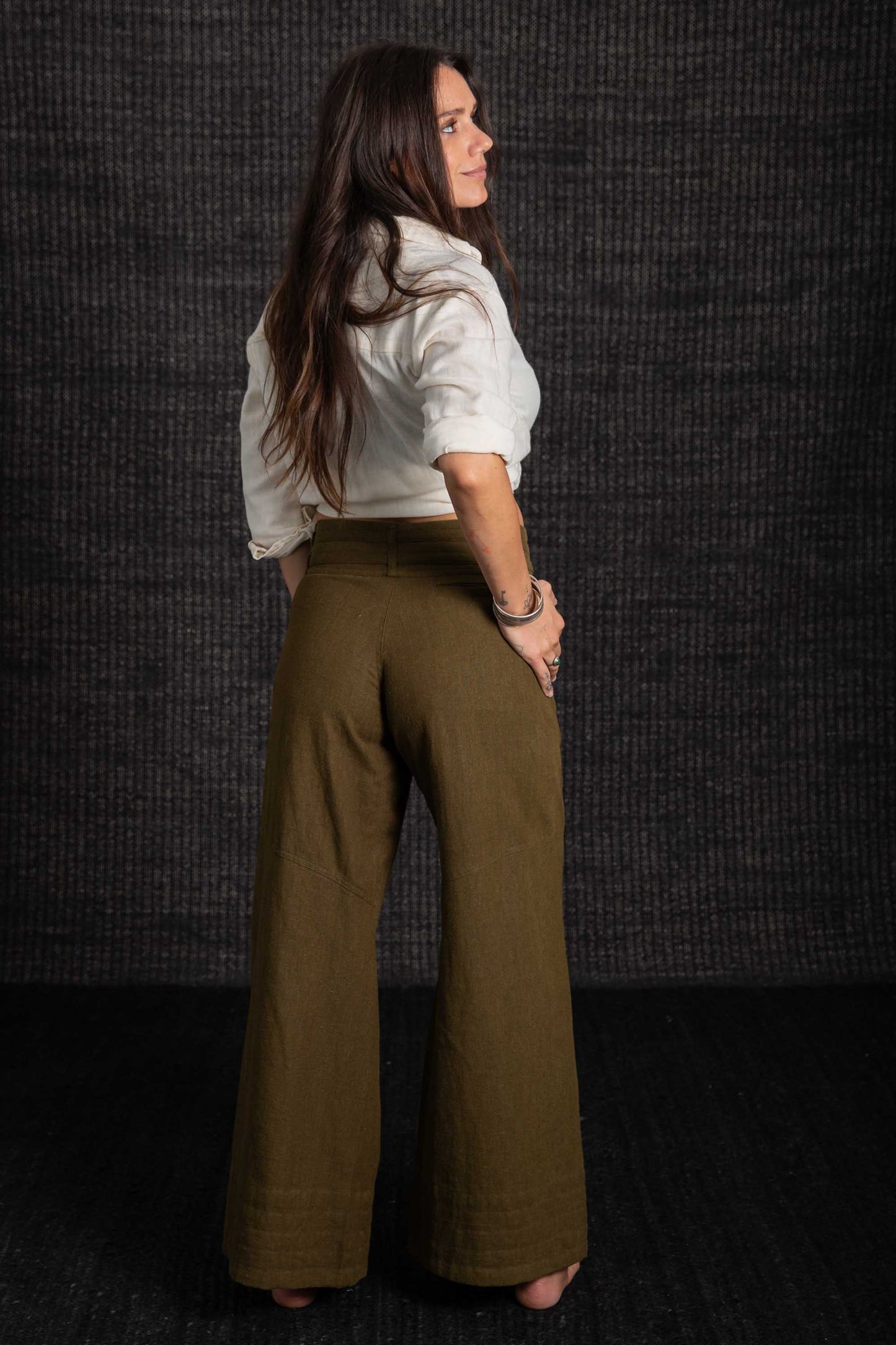 lady in green pants white top with dark bacground