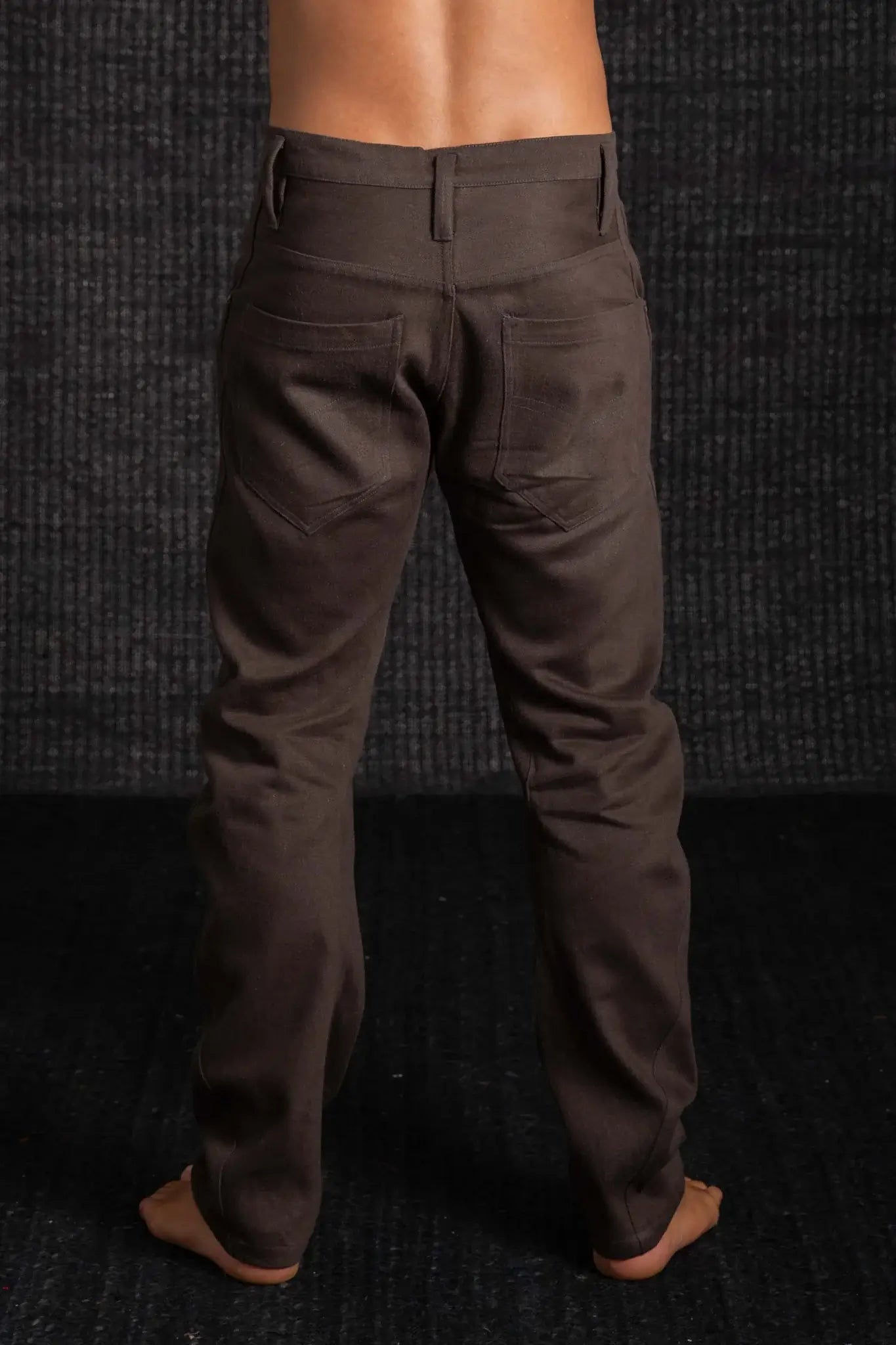 Brown pants worn by a person against a dark textured background