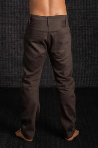 Brown pants worn by a person against a dark textured background