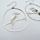 Silver hoop earrings with bird designs on a light gray background