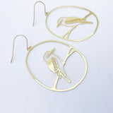 Gold bird-shaped earrings on a light gray background