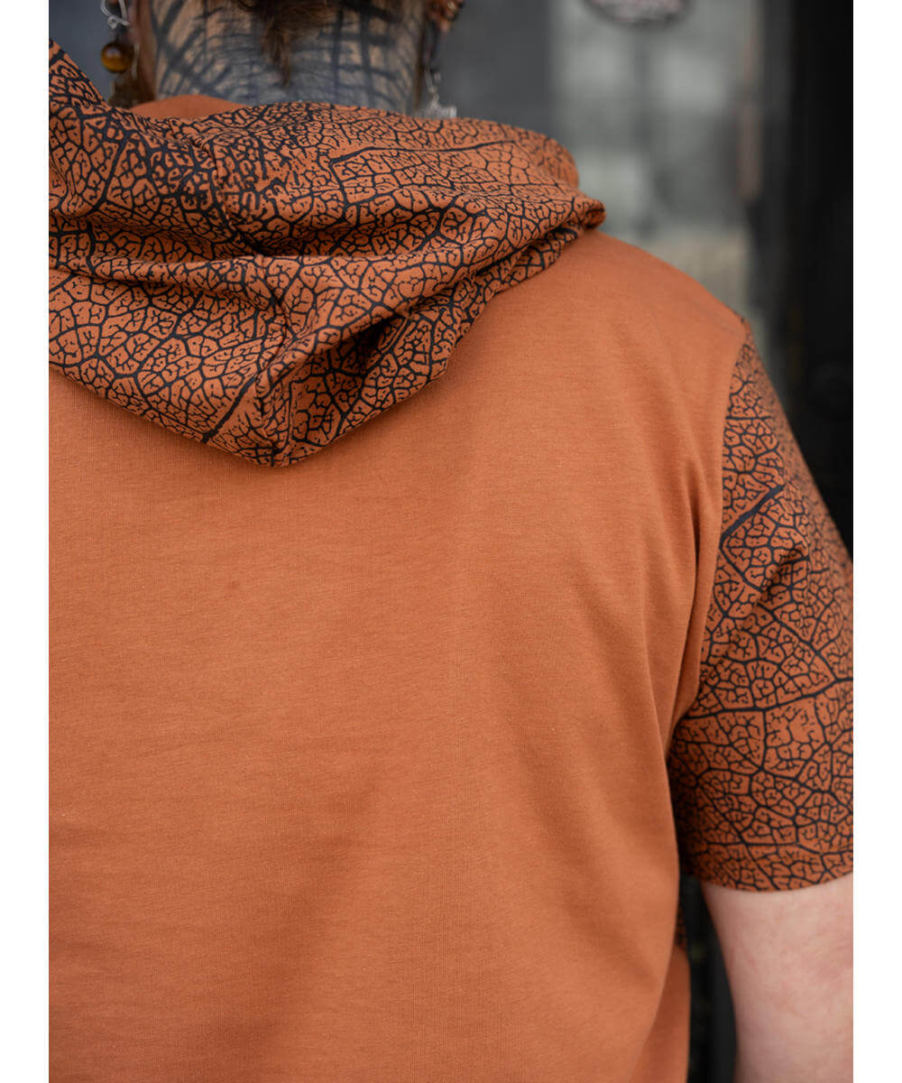 Person wearing a brown shirt with patterned sleeves and hood.