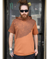 Man wearing a brown and orange patterned hoodie in front of a door.