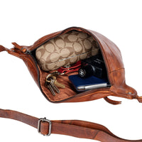 Brown leather bag with visible brand logo, keys, and a phone on a white background