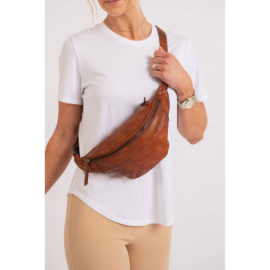 Person wearing a brown leather waist bag on a white background