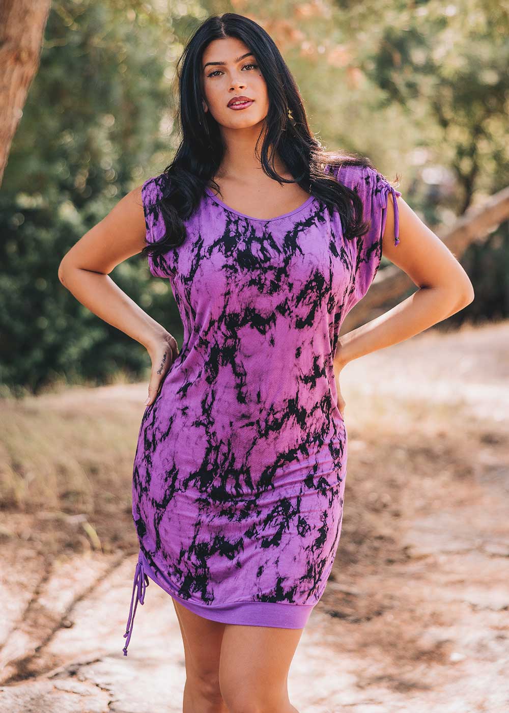 Woman wearing a purple and black tie-dye dress outdoors.
