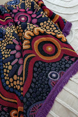 Close-up of a colorful embroidered fabric with intricate patterns on a white background.