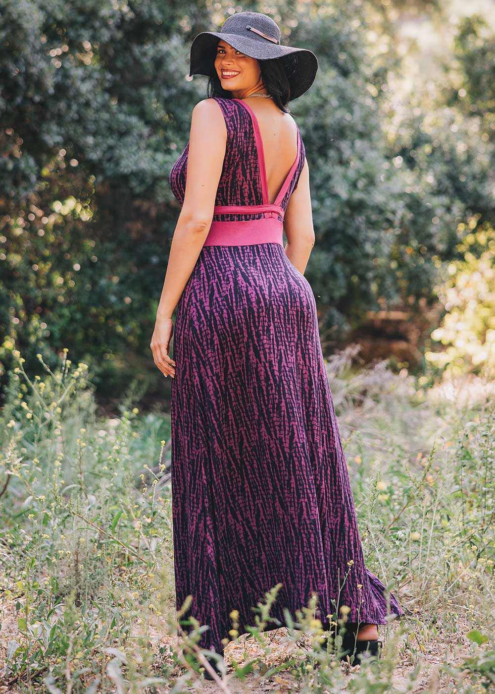 Woman in a purple dress with open back standing in a natural setting