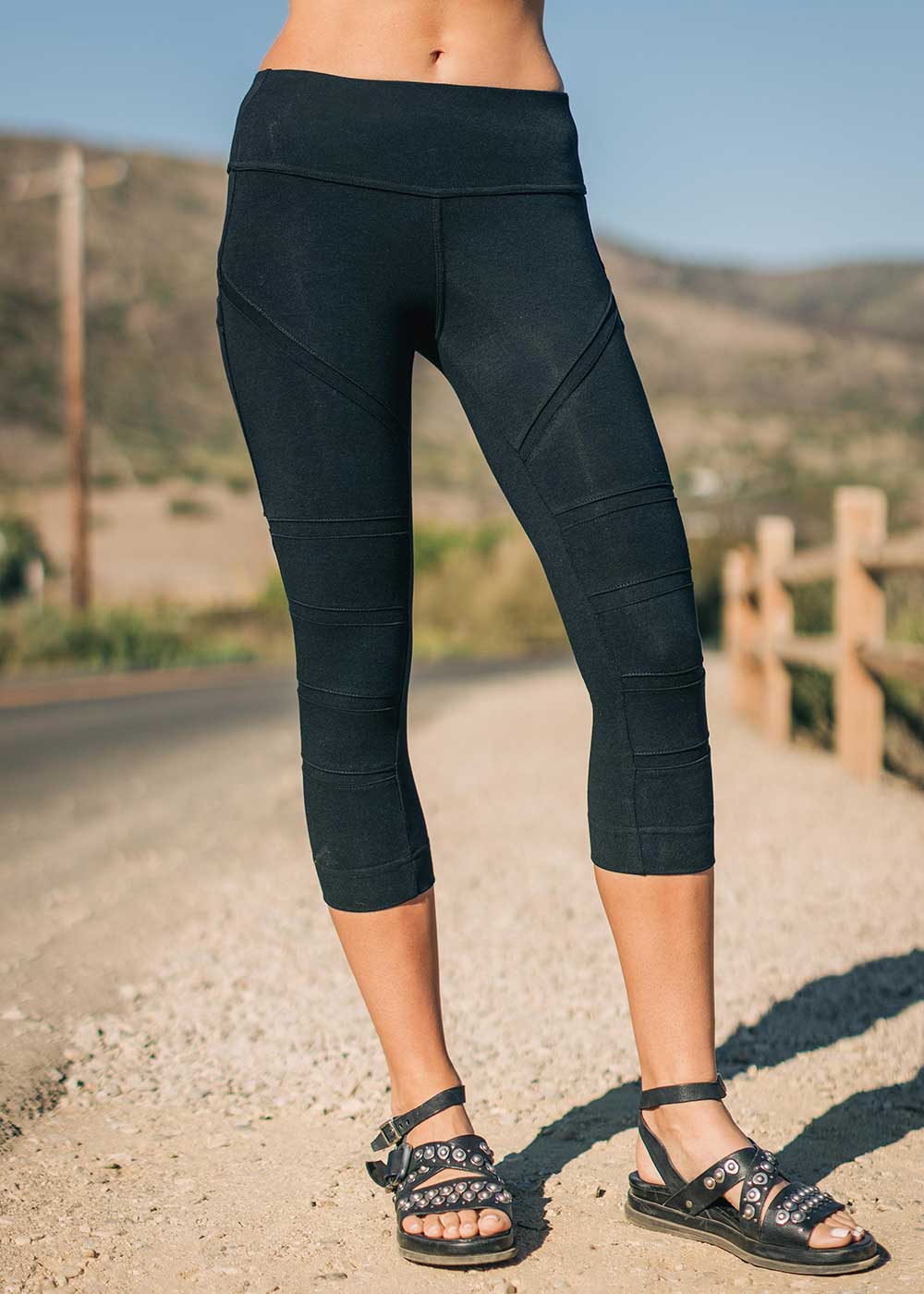 Person wearing black capri leggings on a road with a scenic background