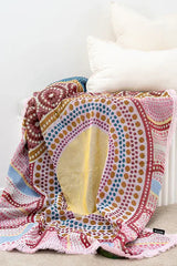 Colorful patterned blanket draped over a pet bed on a white surface