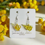 Yellow glass earrings on a branded card with yellow flowers in the background