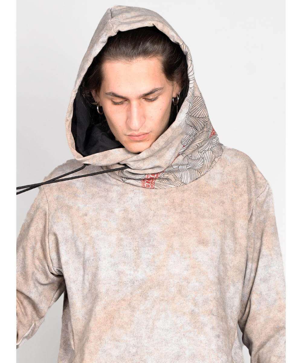 Person wearing a beige hoodie with a patterned scarf around their neck on a white background