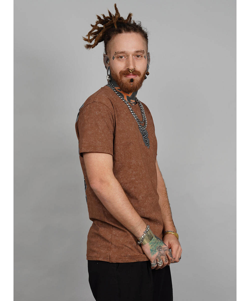 Man with dreadlocks wearing a brown shirt and multiple necklaces on a gray background