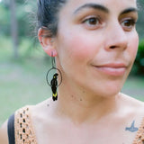 Person wearing a unique earring with a design, outdoors.