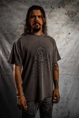 Man wearing a gray t-shirt with a geometric design against a textured wall.