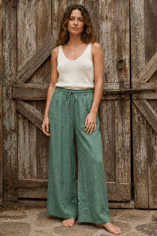 lady in green pants and white singlet infront of a rustic wooden door