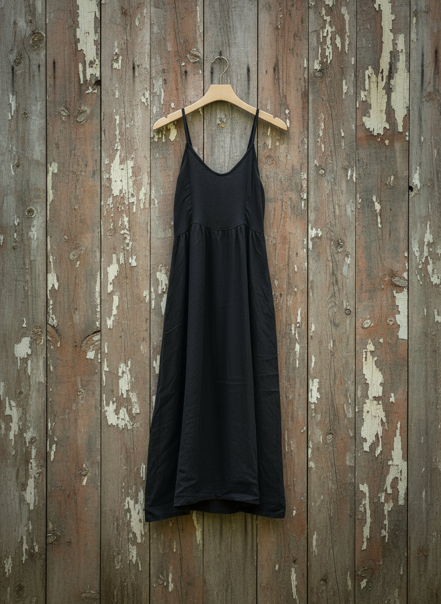 black dress on hanger on a wooden wall

