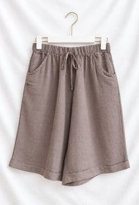 Close-up of women's linen Bermuda shorts in brown highlighting the natural fabric.