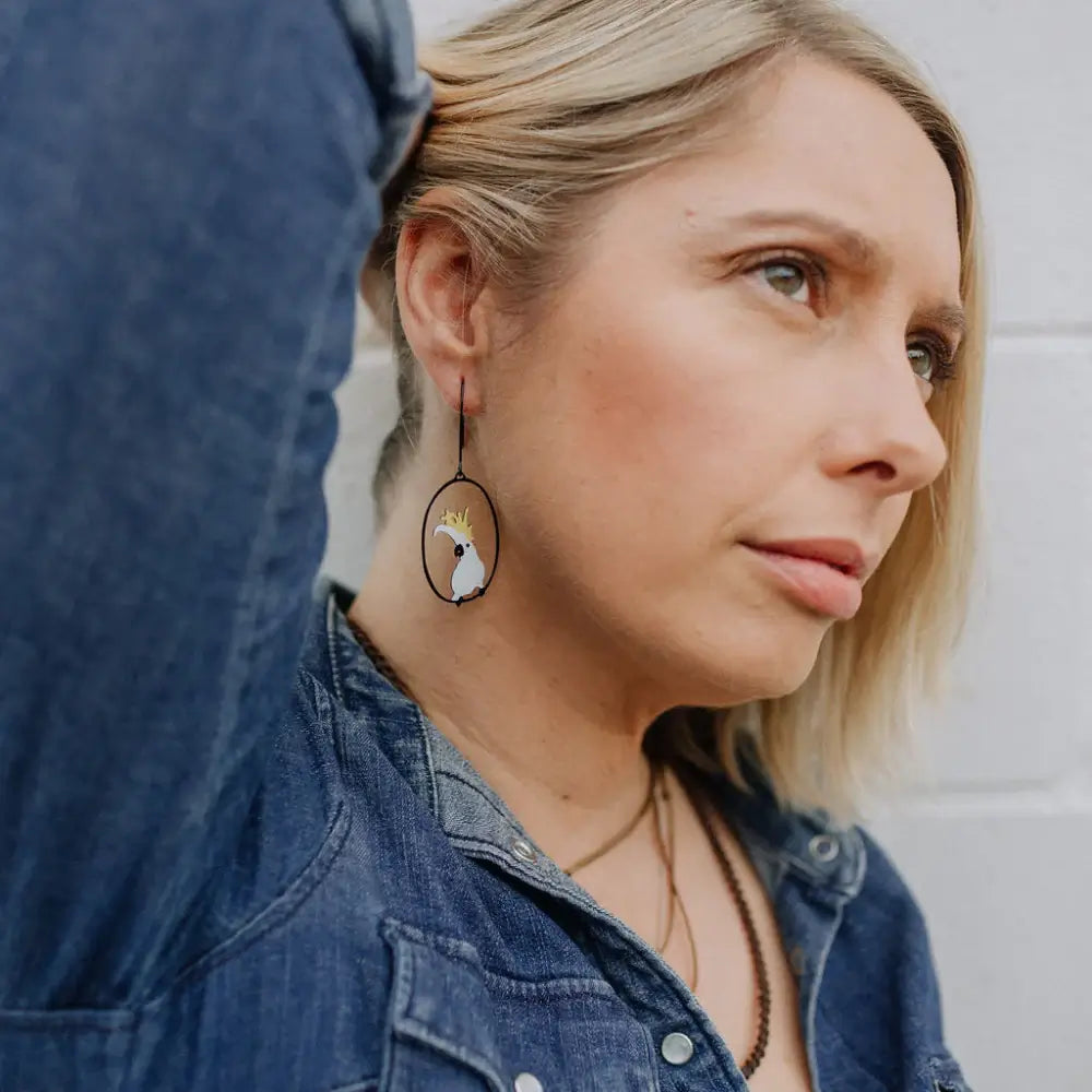 Woman wearing a denim jacket and earrings with a neutral background