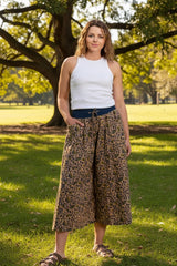 Woman wearing a white sleeveless top and leopard print skirt on a white background