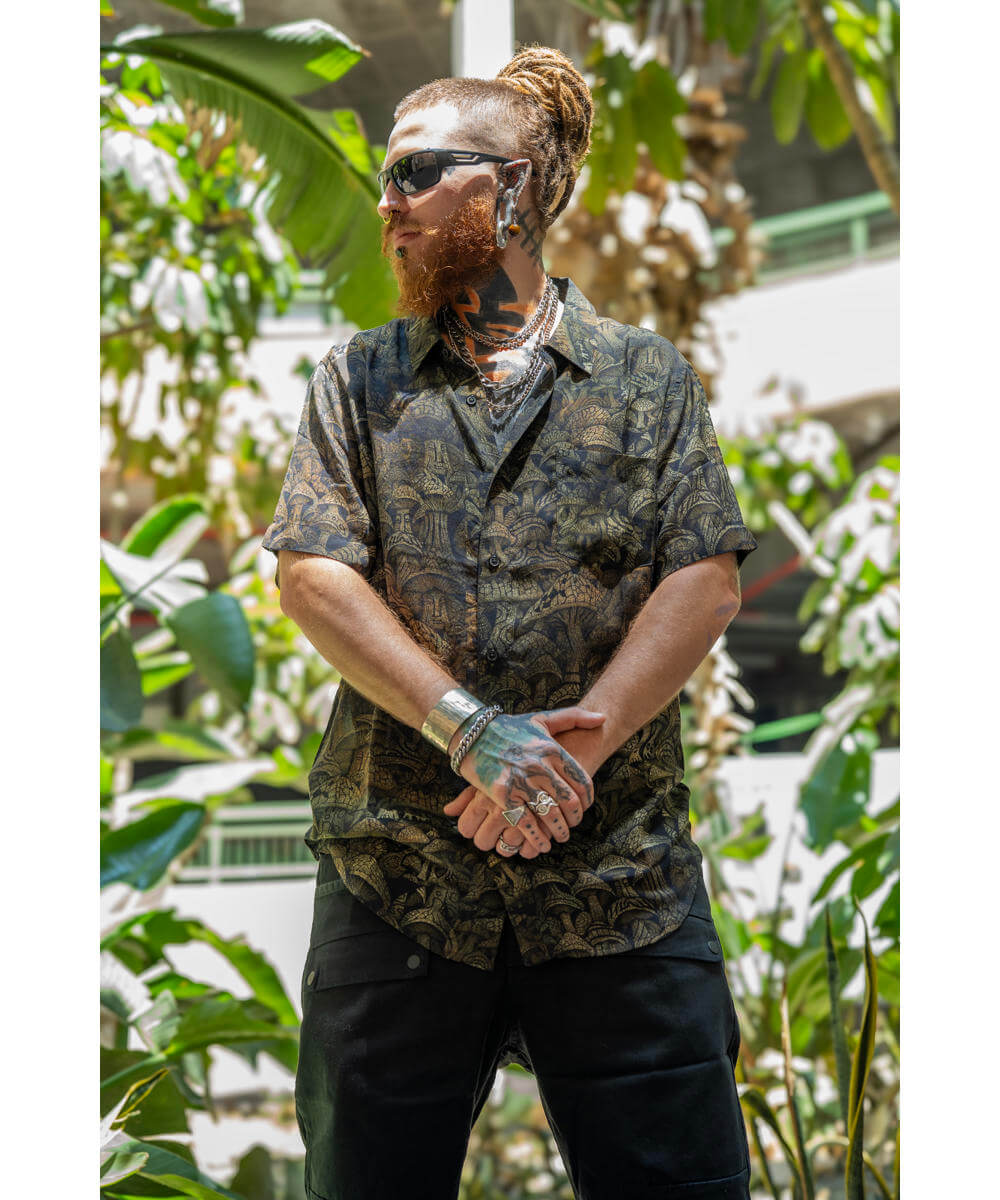 Person wearing a mushroom print shirt and sunglasses in a tropical setting