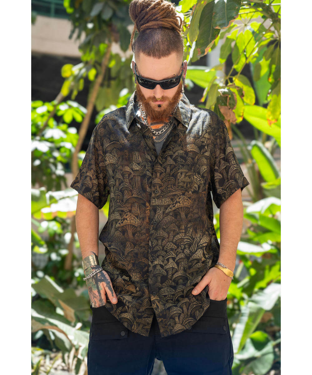 Man wearing a patterned shirt and sunglasses in a forest setting