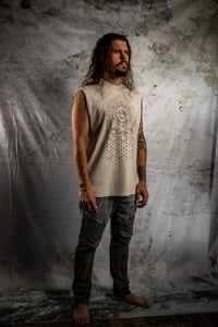 Man wearing a sleeveless beige top with intricate patterns against a textured gray background