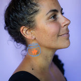 Close-up of a person wearing a fishbowl earring with a fish illustration.
