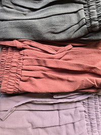 Stack of folded fabric in green, rust and mauve.