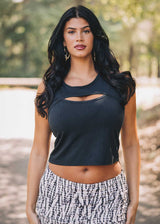 Woman wearing a black sleeveless top with cut-out design outdoors