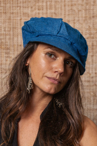Woman wearing a blue cap against a textured beige background