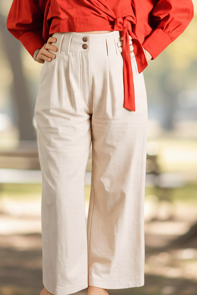 Person wearing a red blouse and white pants on a black background