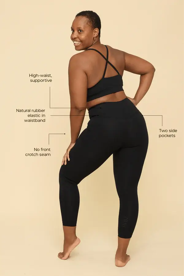 Woman wearing black athletic leggings with text highlighting features on a beige background