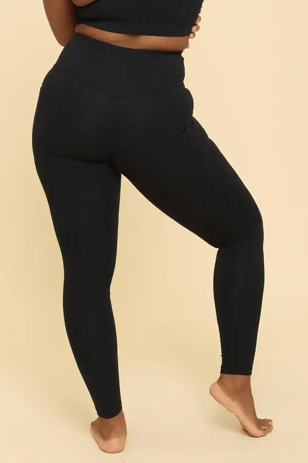 Person wearing black leggings on a beige background